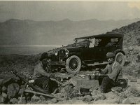 Shorty Harris and companion eating next to an automobile, Death Valley, 1920s